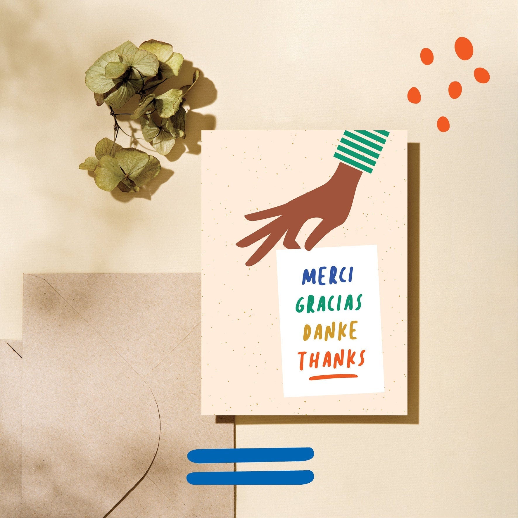 thank you card with a hand holding a white paper with a text in it that says Merci, Gracias, Danke