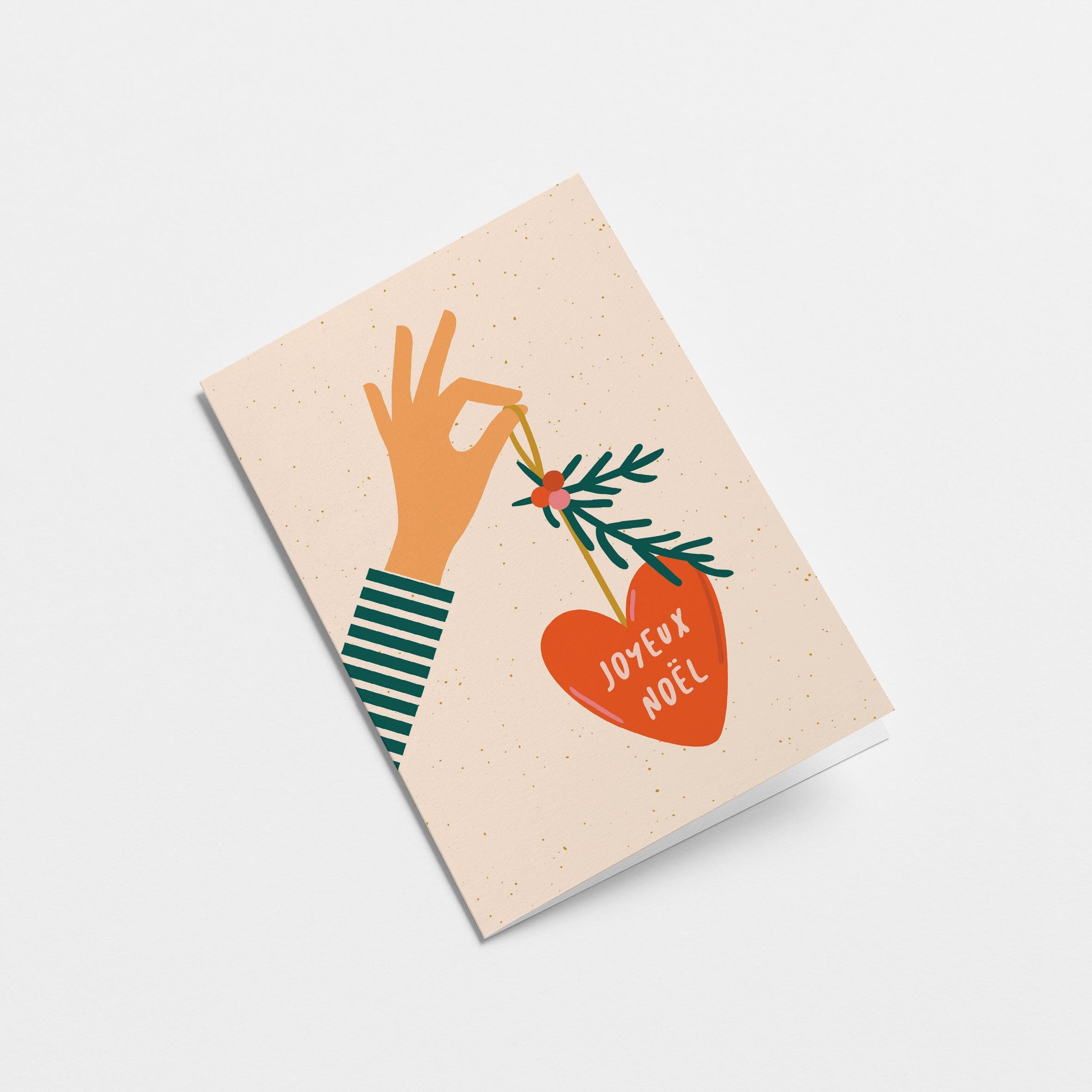 christmas card with a hand holding red christmas tree ornament and a text in it that says be merry and bright