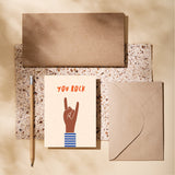 birthday card with a brown hand and a gesture of sign of the horns with a text that says you rock