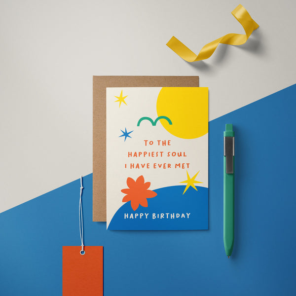 birthday card with yellow sun green bird yellow stars blue figures and a text that says to the happiest soul i have ever met happy birthday