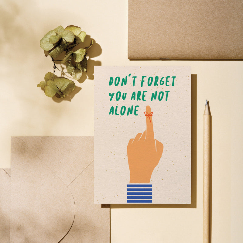 friendship card with a finger tied with a red string with a text that says don’t forget you are not alone