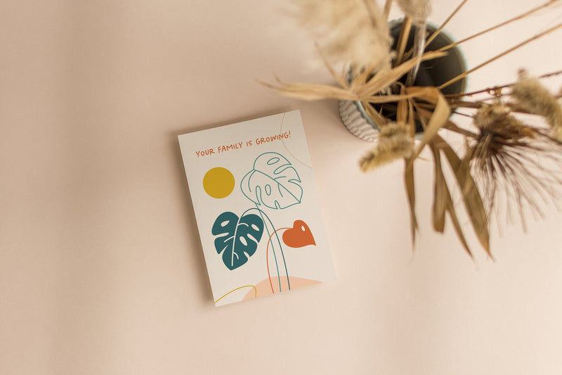 new baby card with green leaf drawings and a little red leaf with yellow sun and a text that says your family is growing