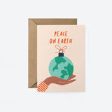 greeting card with gift wrapped earth on the palm of a brown hand with a text that says peace on earth