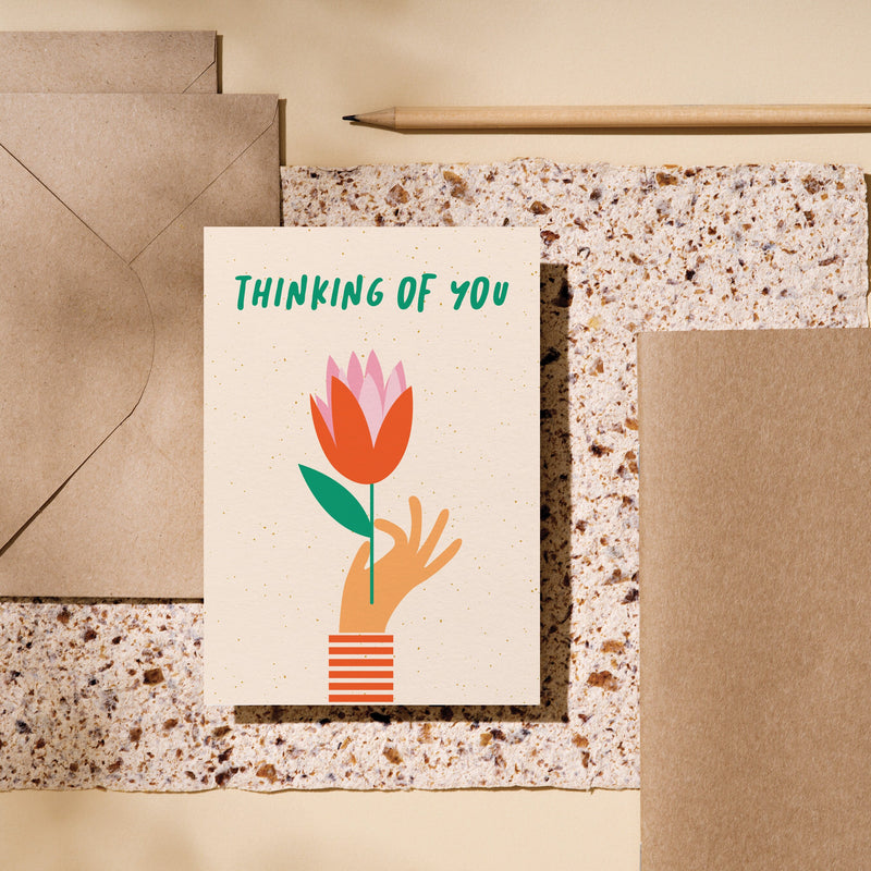 Thinking of you card with a hand holding red tulip and a text that says thinking of you