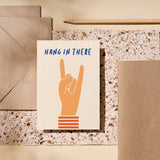 encouragement card with a hand and a gesture of sign of the horns with a text that says hang in there